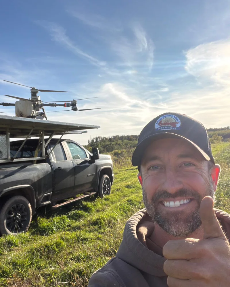 Chad Mooney in a field beside a truck carrying a spray drone